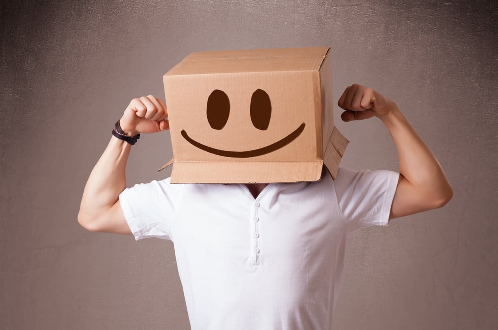 Young man standing and gesturing with a cardboard box on his head with smiley face